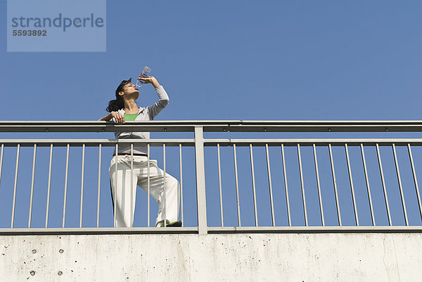 Deutschland  Nordrhein-Westfalen  Düsseldorf  Junge Frau Trinkwasser auf Brücke