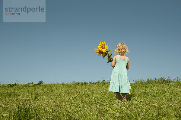 Mädchen im Gras stehend mit Sonnenblume