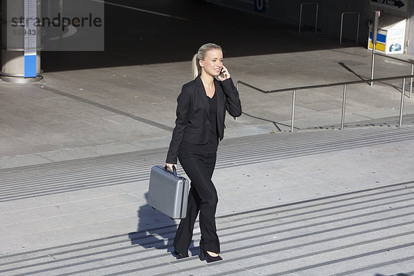 Geschäftsfrau auf der Treppe mit Aktentasche und Gespräch am Handy  lächelnd