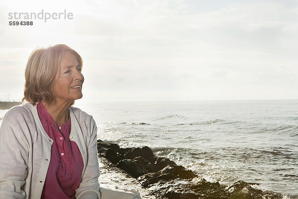 Spanien  Mallorca  Seniorin am Meer sitzend  lächelnd