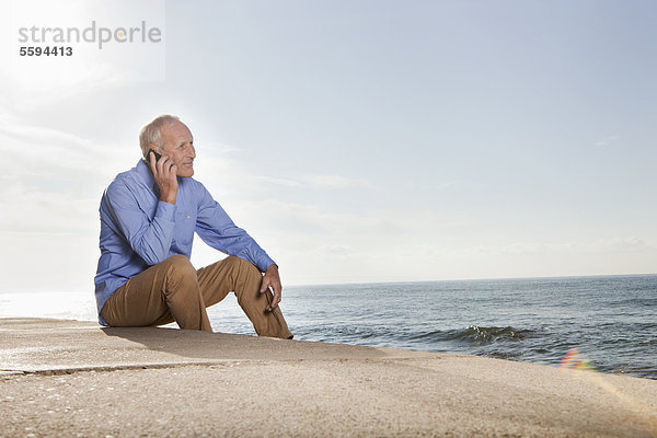 Spanien  Mallorca  Senior Mann auf dem Handy am Meer