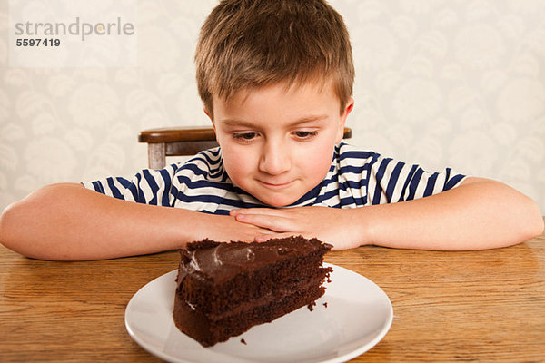 Junge schaut sich ein Stück Schokoladenkuchen an.