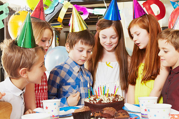 Kinder um den Kuchen bei der Geburtstagsfeier