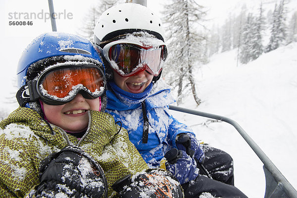 Schneebedeckte Kinder im Skilift