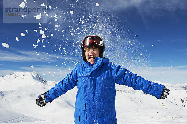 Junge jubelt auf schneebedecktem Berggipfel