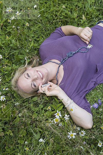 Frau spricht auf dem Handy im Gras