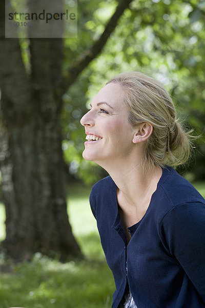 Lächelnde Frau im Freien sitzend