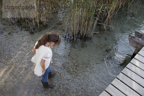 Mädchen in Stiefeln beim Spaziergang im Teich