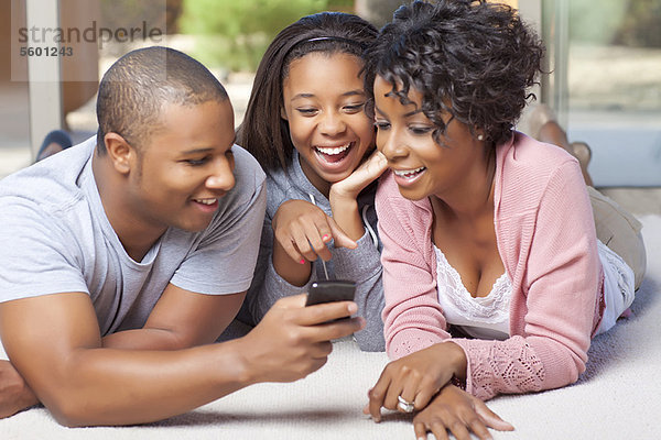 Lächelnde Familie mit dem Handy zusammen
