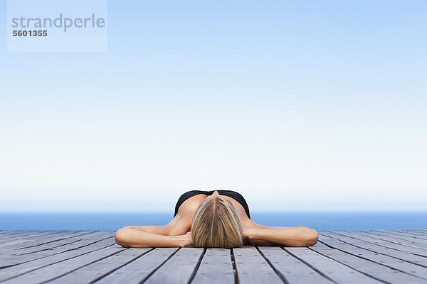 Frau beim Sonnenbaden auf dem hölzernen Pier