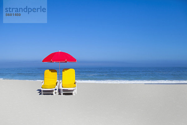 Leere Liegestühle und Sonnenschirm am Strand