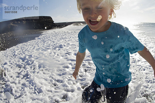 Junge spielt in Wellen am Strand