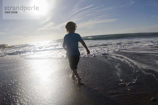 Junge spielt in Wellen am Strand