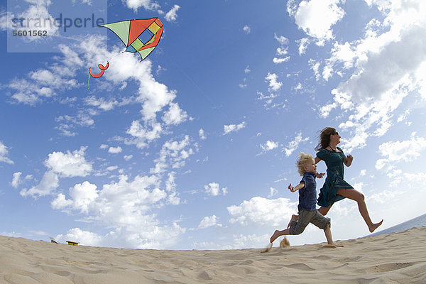 Mutter und Sohn beim Drachenfliegen am Strand