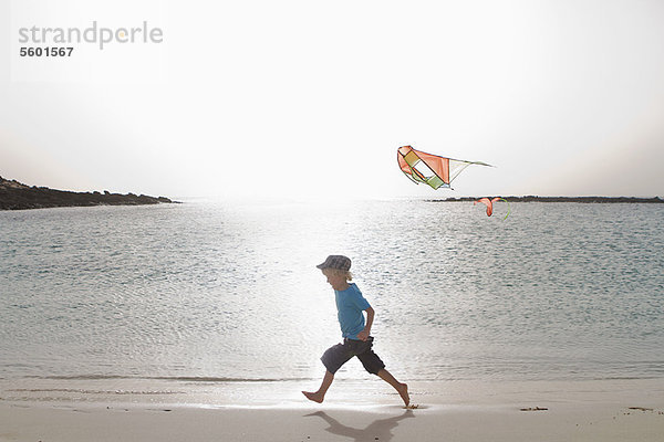 Junge beim Drachenfliegen am Strand