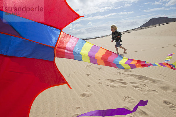 Junge beim Drachenfliegen am Strand