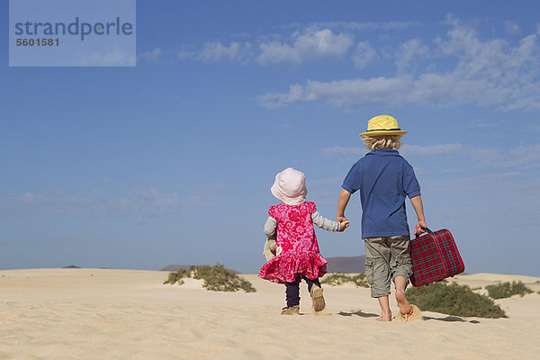 Geschwister  die gemeinsam am Strand spazieren gehen