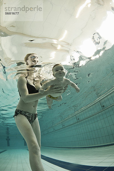 Frau bringt dem Baby das Schwimmen im Pool bei