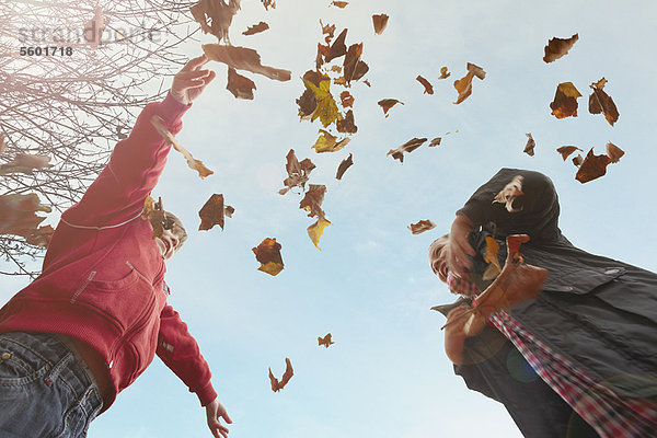 Kinder spielen mit Herbstblättern