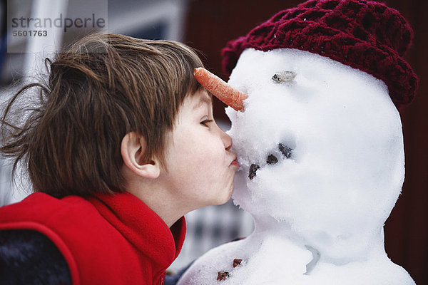 Nahaufnahme des Jungen  der den Schneemann küsst