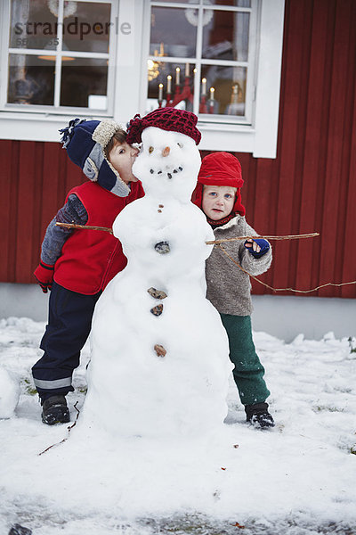 Kinder stehen mit Schneemann