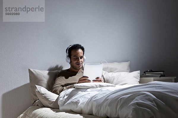 Mann mit Tablet-Computer im Bett