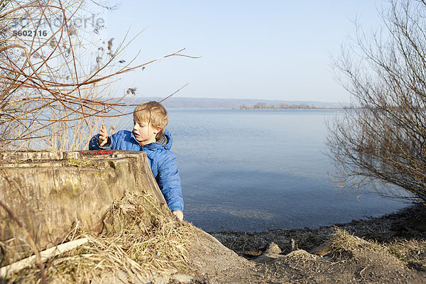 Junge spielt mit Beeren am See