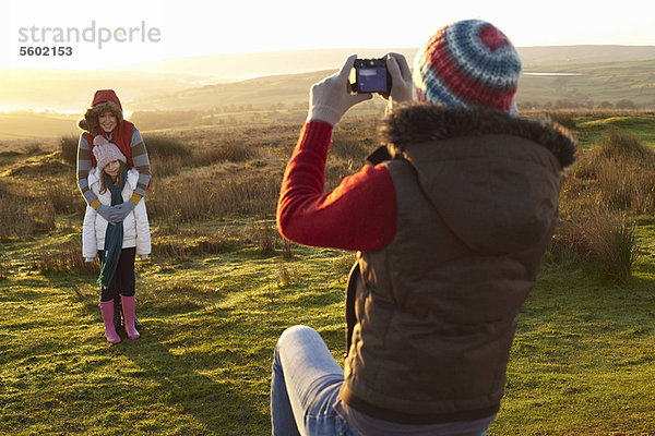 Frau beim Fotografieren der Familie im Freien