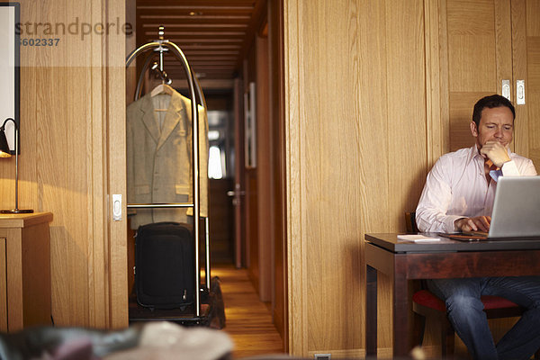 Mann mit Laptop im Hotelzimmer