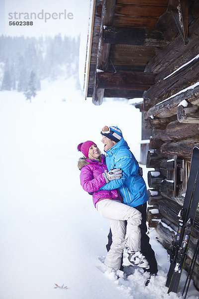 Lächelndes Paar umarmt sich im Schnee