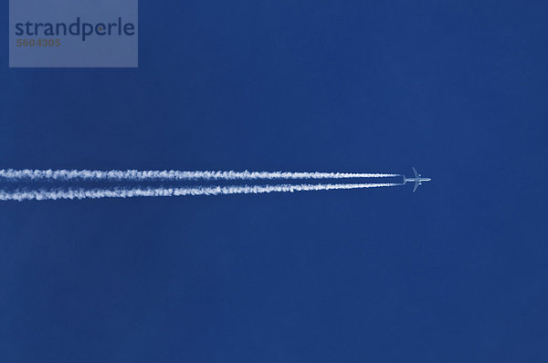 Doppelter Kondensstreifen hinter Flugzeug am blauen Himmel