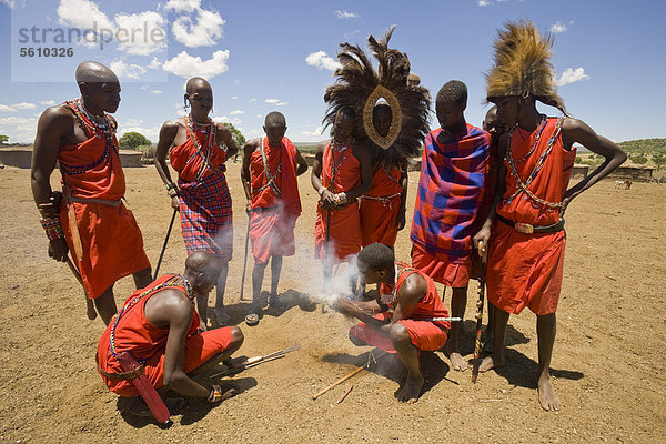 Massai-Stammesangehörige entzünden ein Feuer außerhalb eines Dorfes  Masai Mara  Kenia  Afrika