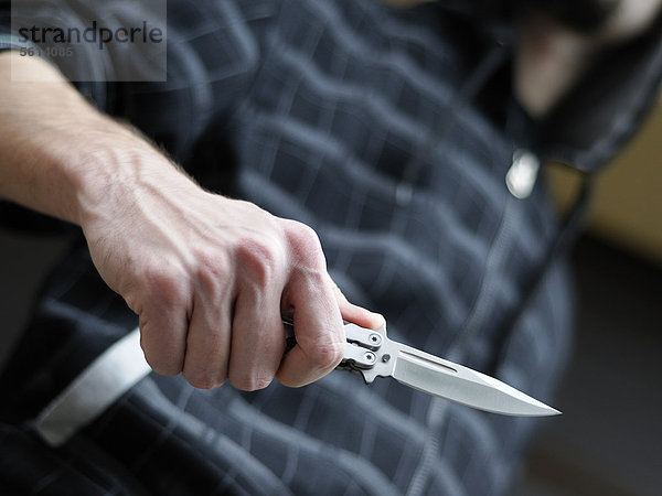 Messerkriminalität  Mann mit Kaputze schwingt ein Butterflymesser  Klappmesser