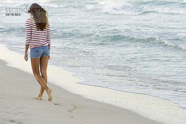 Frau beim Spaziergang am Strand  Rückansicht