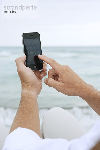 Mann mit Smartphone am Strand  abgeschnitten