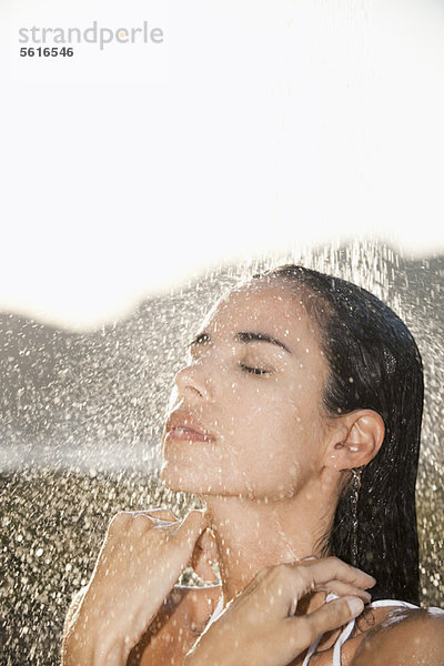 Erwachsene Frau mit geschlossenen Augen beim Duschen im Freien
