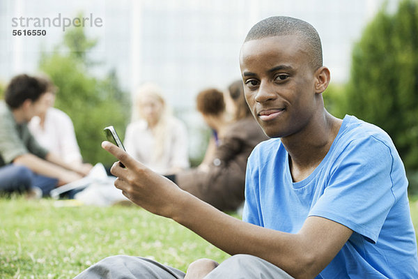 Junger Mann mit Handy  Menschen im Hintergrund  Portrait