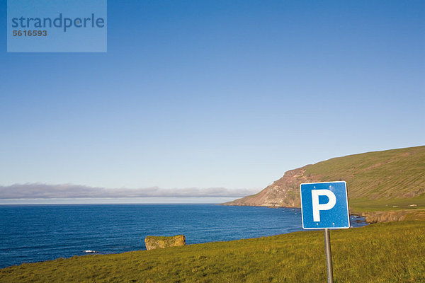Parkplatzschild in Küstenlandschaft  Island