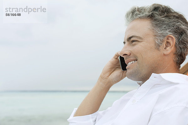 Mann spricht am Strand am Handy