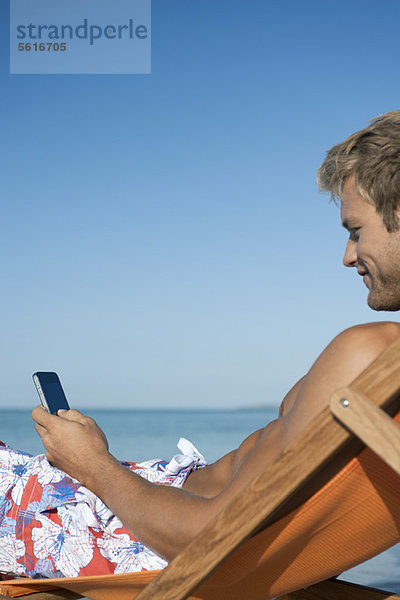Junger Mann SMS am Strand