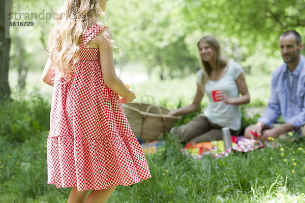 Mädchen beim Picknick mit Eltern im Freien  Rückansicht