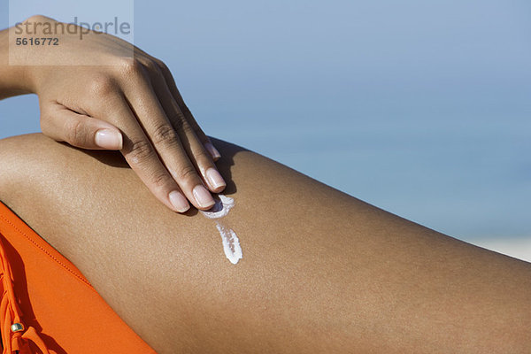 Frau mit Sonnenschutz am Strand  beschnitten
