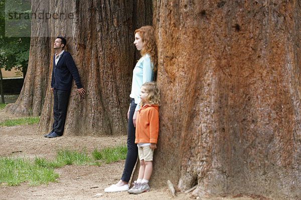 Vater lehnt im Hintergrund an Baumstamm  Frau und Tochter getrennt im Vordergrund