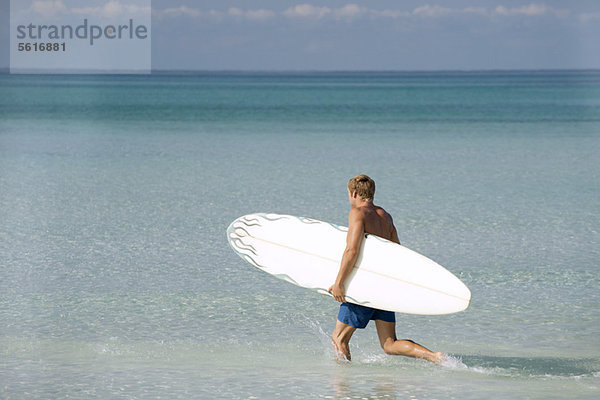 Mann mit Surfbrett im Wasser  Rückansicht