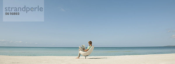 Mann liest Buch am Strand