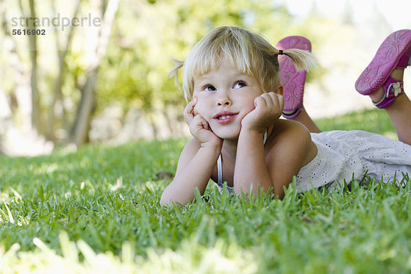 Kleines Mädchen auf Gras liegend  aufblickend