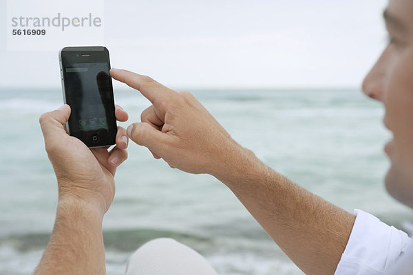 Mann mit Smartphone am Strand