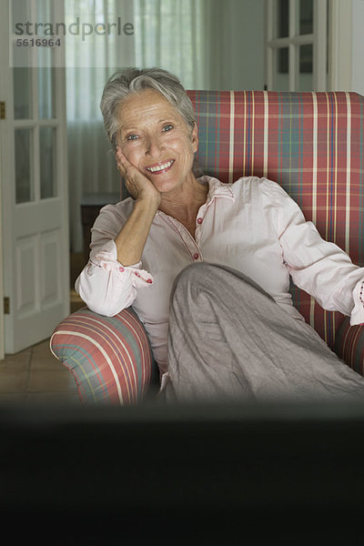 Lächelnde Seniorin im Sessel sitzend