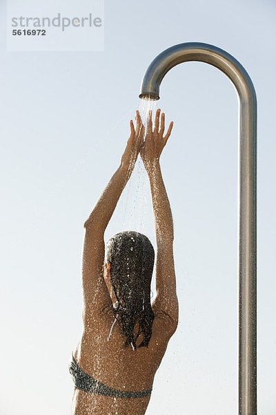 Frau im Bikini-Top beim Duschen im Freien