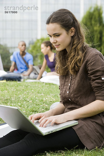 Junge Frau mit Laptop im Freien  Menschen im Hintergrund  Portrait